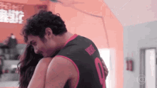 a man wearing a number 0 jersey hugs a woman