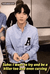 a young man in a blue shirt is sitting in a chair and talking .