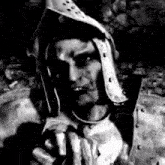 a black and white photo of a man in armor holding a gun .