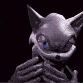 a person is holding a statue of a cat with a blue eye in the dark .