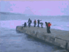 a group of people standing on a pier overlooking the ocean .