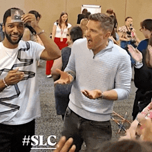 a man holds up a picture of a woman with the hashtag #slc on the bottom right