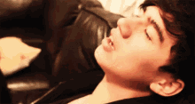 a close up of a man laying on a couch with his eyes closed