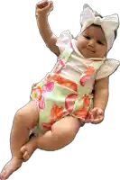 a baby wearing a floral outfit and a white headband is laying down