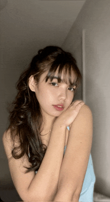 a woman in a blue tank top holds her hand on her shoulder