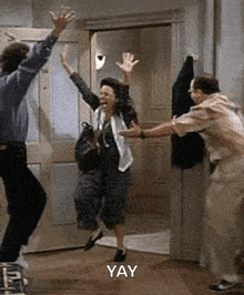 a group of people are jumping in the air in a room with the words yay written on the bottom .