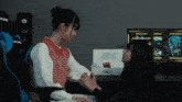 a woman holds another woman 's hand in front of an akracing chair