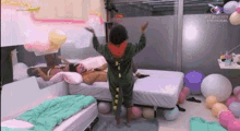 a person in a dinosaur costume is standing in a bedroom with balloons and a bed .