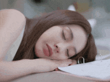 a woman with her eyes closed is laying on a binder
