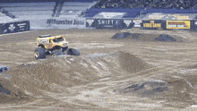 a monster truck is driving down a dirt track in front of a wall that says monster jam