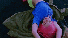 a woman with pink hair and headphones is laying down