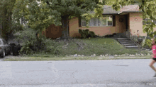 a woman in a pink shirt is running down the street in front of a house