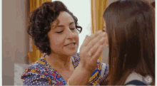 two women are touching each other 's faces and smiling .