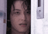 a close up of a man 's face looking out of a white door