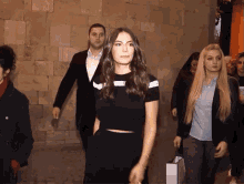 a woman in a black crop top walks with a man in a suit