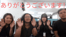 a group of people waving their hands in front of a sign that says ありがとう