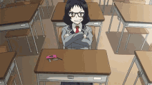 a girl is sitting at a desk in a classroom with her arms crossed .