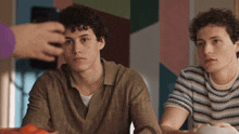 two young men sitting at a table with a bowl of food