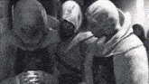 a black and white photo of a group of people in hoods