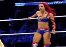 a woman with red hair is standing in a wrestling ring with a crowd watching .