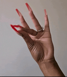 a woman 's hand with long red nails and a silver ring on her finger