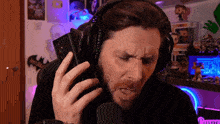 a man wearing headphones talks into a microphone in front of a wall with a picture of a bat on it