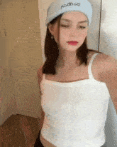 a woman wearing a white tank top and a blue hat that says ncdncd