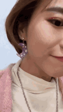 a woman wearing purple earrings with a crescent moon design