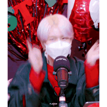 a person wearing a mask and a shure microphone that says now