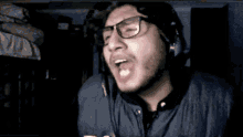 a young man wearing glasses and headphones is making a funny face .