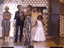 a group of people are standing around a woman on a stage .