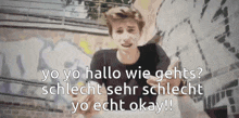 a young man stands in front of a graffiti covered wall with the words yo yo hallo wie gehts