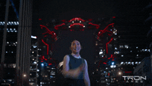 a poster for tron ares shows a woman standing in front of a robot