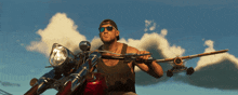 a man wearing sunglasses is riding a motorcycle with a plane in the background