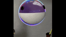 a purple and white ball is floating in the air against a wall .