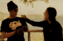 a man wearing a shirt that says grand on it is being touched by a woman