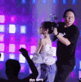 a man is fixing a woman 's hair in front of a crowd of people