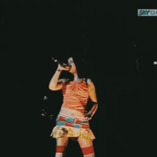 a woman is singing into a microphone in front of a sign that says sky on it