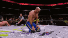 a wrestler is kneeling down in a ring with a referee behind him and a sign that says final battle