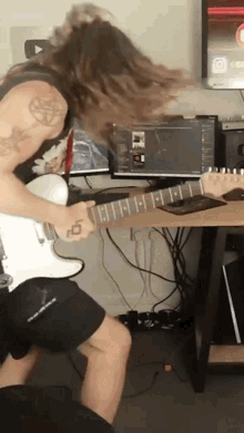 a man playing a guitar with a pentagram tattoo on his shoulder