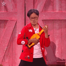 a man in a red jacket is holding a yellow toy chicken