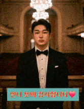 a man in a tuxedo stands in front of a sign that says ' i love you ' in korean