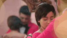 a woman in a pink dress is kissing a man in a pink suit