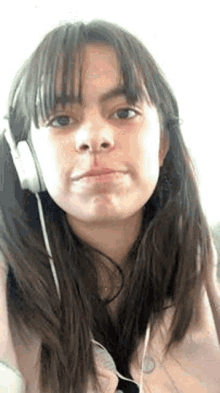a young woman is wearing headphones and making a face .