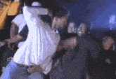 a man in a white shirt is dancing in a crowd of people in a club .