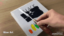 a person is painting a picture with the word black on it