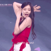 a woman in a red top and white shorts is dancing on a stage with the words jeemin de azul in the corner