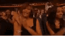 a group of women are standing in a crowd applauding .