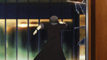 a man in a black coat runs through a broken glass door