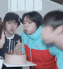 a group of young boys are blowing out candles on a birthday cake .